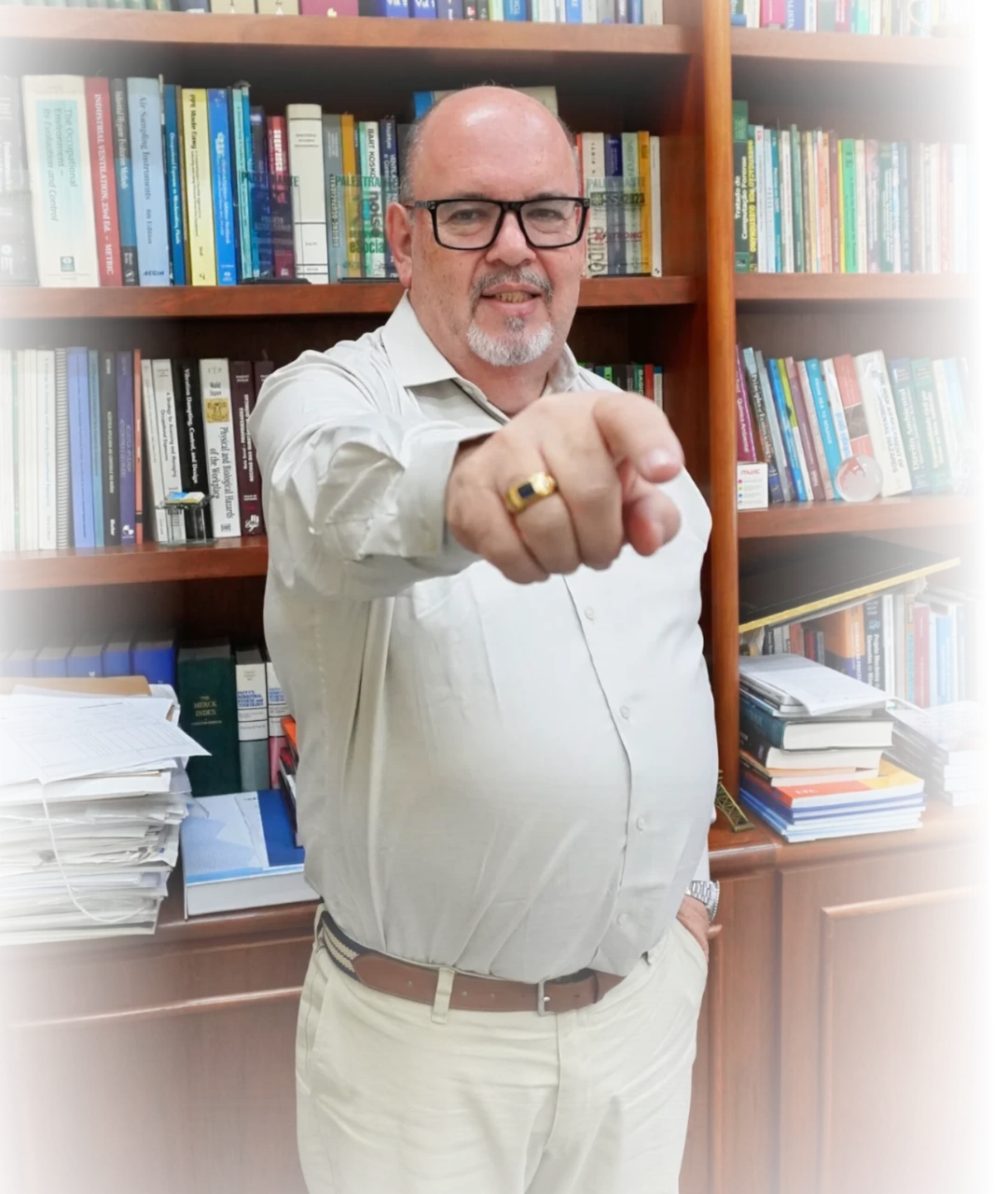 Professor Antonio Carlos Vendrame diante de sua estante de livros, apontando para a câmera